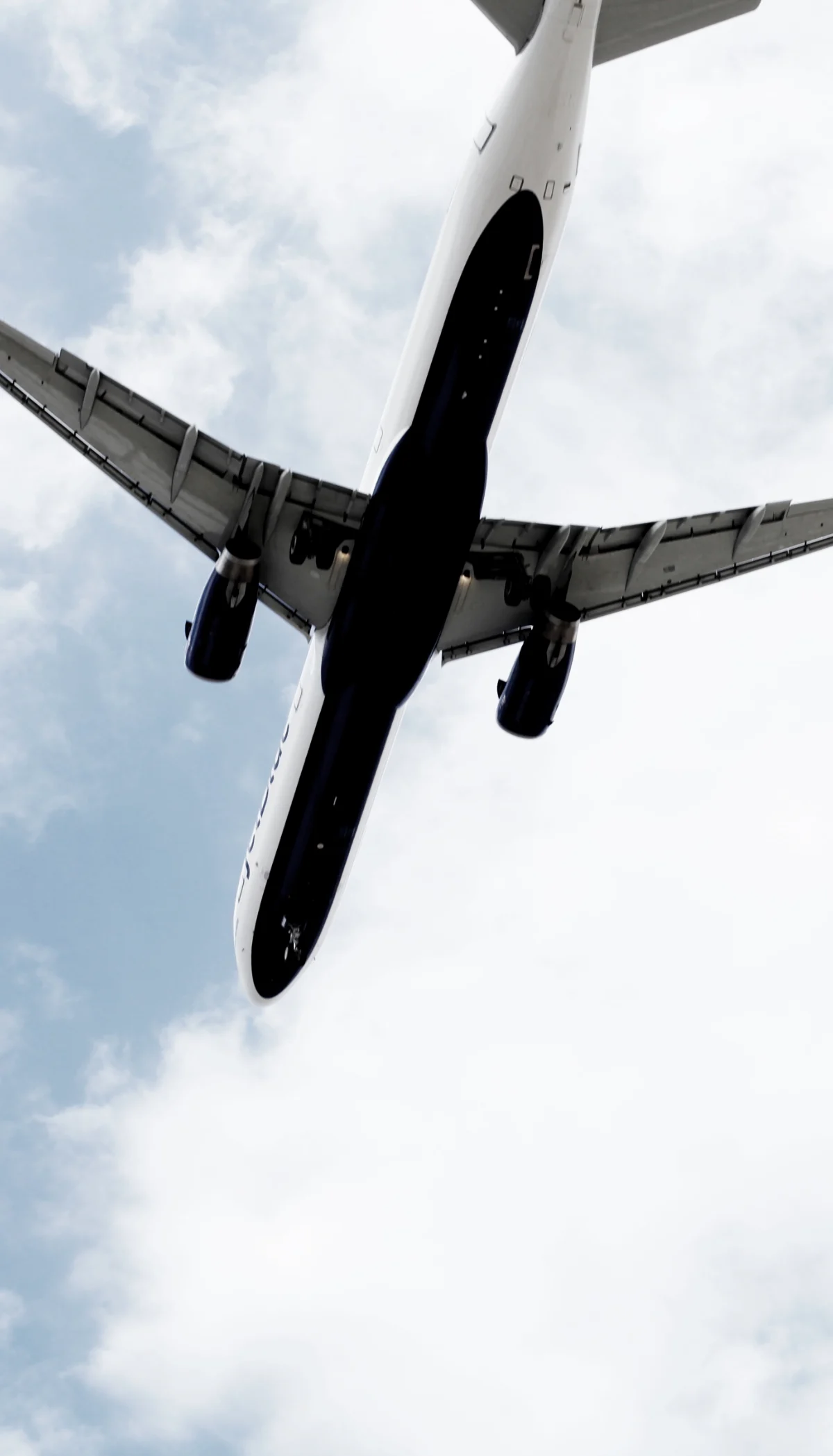 Passenger jet seen from below against clouds